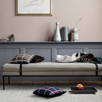 Neutral beige and gray tones with black, checkered, and solid-patterned pillows on a minimalist daybed.