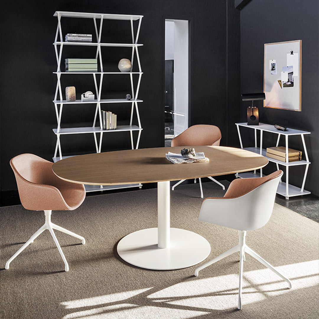 Round wooden table with light brown finish, surrounded by white and soft pink modern chairs in a stylish black room.