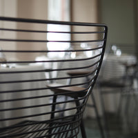 Black metal chair with sleek horizontal lines and wooden accents, set in a modern dining environment.