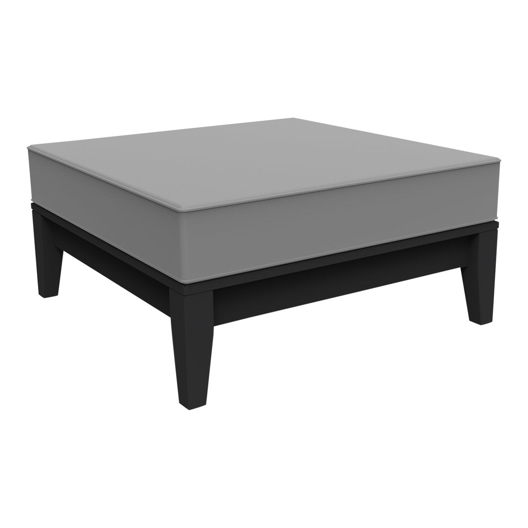 Square coffee table with a sleek gray cushion and contrasting black wooden legs. Modern, minimalistic design. 