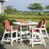 White outdoor dining set with orange cushions, set against a lush green landscape. Ideal for stylish outdoor gatherings.