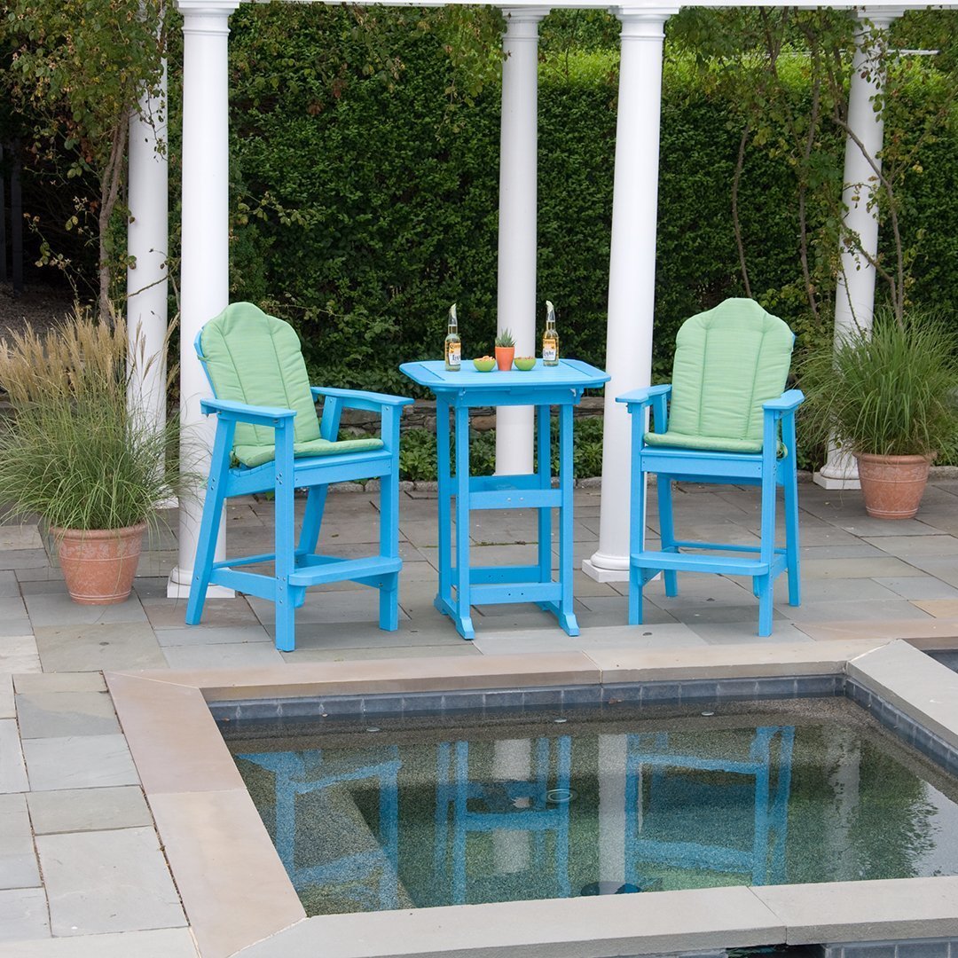 Teal outdoor bar stools with green cushions, set beside a blue table, against a landscaped patio backdrop.