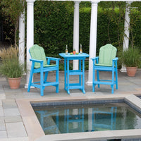 Teal outdoor bar stools with green cushions, set beside a blue table, against a landscaped patio backdrop.