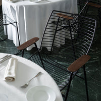 Black wire chair with natural wood armrests, featuring a modern, sleek design. Ideal for stylish dining spaces.