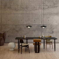 Modern dining space with black table, neutral walls, green and tan chairs, and sleek pendant lighting.
