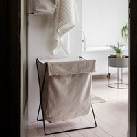 Beige laundry hamper with a minimalist design, featuring a solid color fabric and a sleek black metal frame.