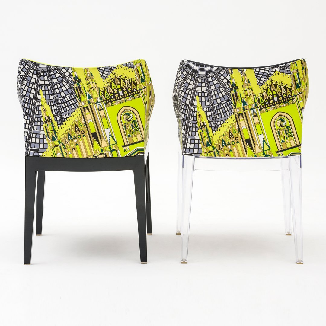 Vibrant yellow and black chair with intricate cityscape pattern, featuring a modern design and clear legs.