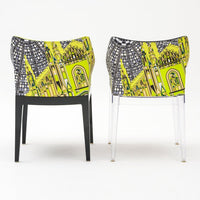 Vibrant yellow and black chair with intricate cityscape pattern, featuring a modern design and clear legs.