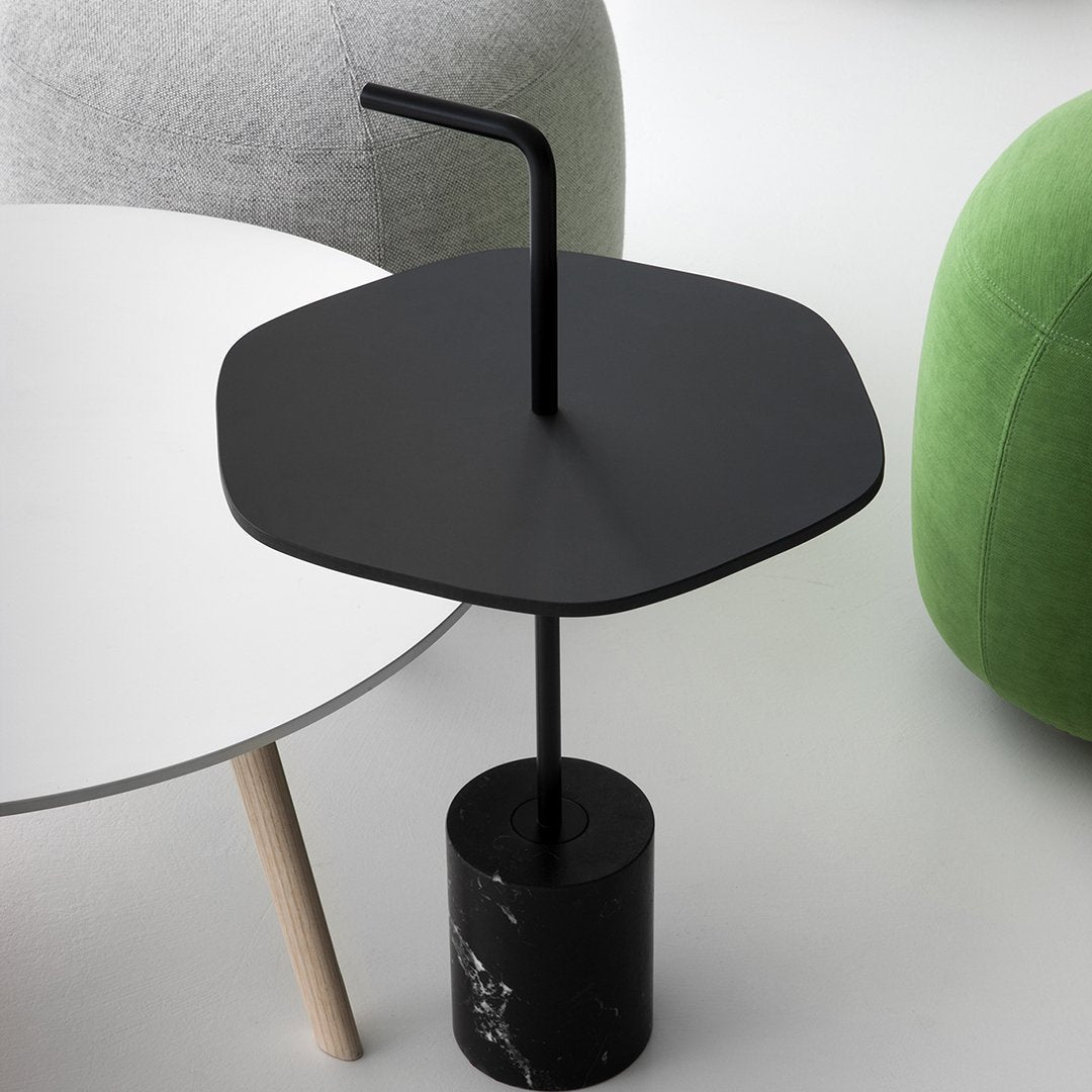 Black hexagonal side table with a marble base and minimalist design, complemented by soft gray and green furniture.