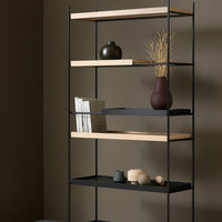 Modern black metal shelf with natural wood accents, featuring a minimalist design against a warm neutral background.