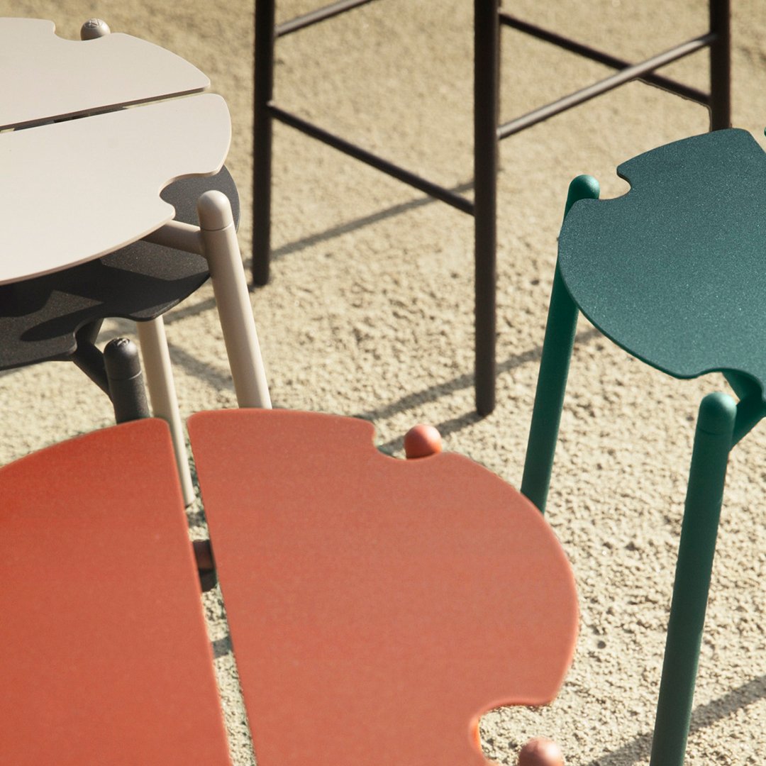 Colorful modern stools featuring coral, green, grey, and white patterns on a textured surface.