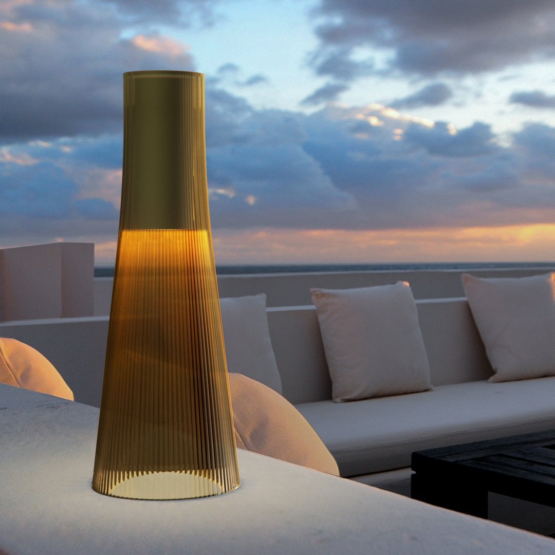 Elegant golden lamp with a ribbed pattern, casting a warm glow against a serene outdoor sunset backdrop.