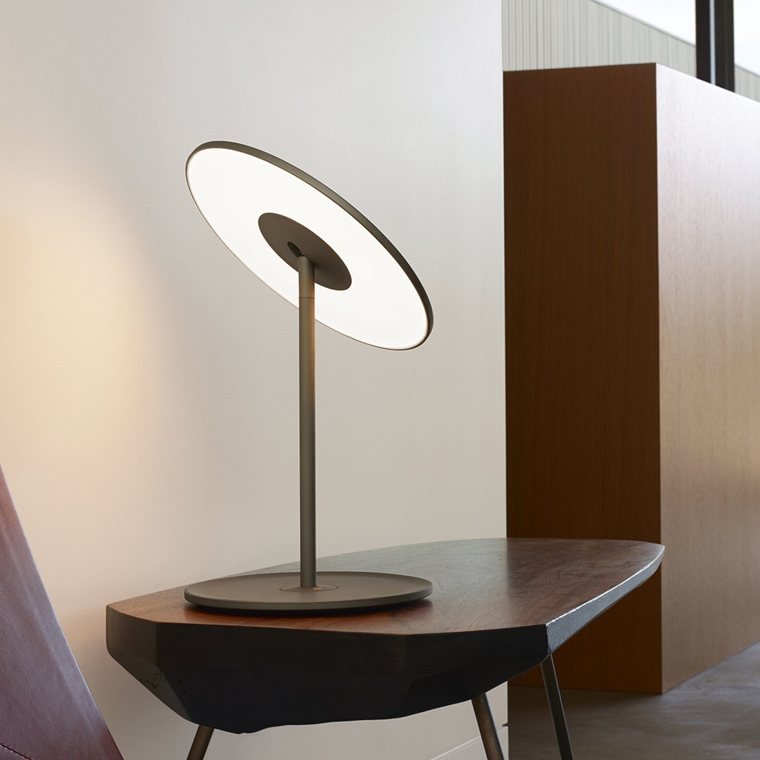 Modern table lamp featuring a sleek gray base and a circular white light design, complementing minimalist decor.