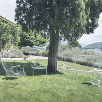 Translucent acrylic outdoor furniture in clear and green hues, set against a lush garden backdrop.
