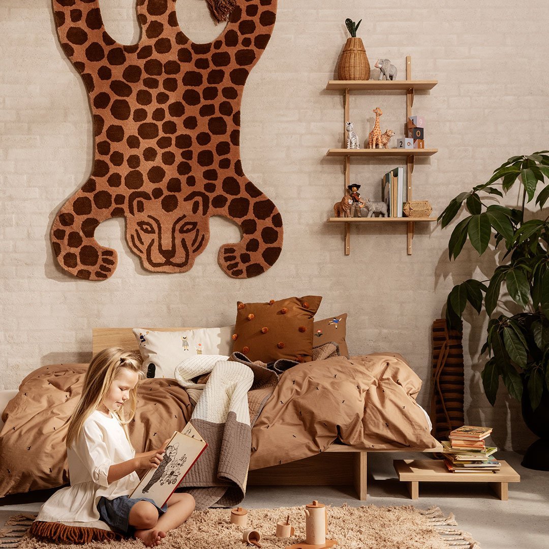 "Leopard print wall decor in earthy tones with brown and beige accents on bedding and cushions in a cozy room setting."