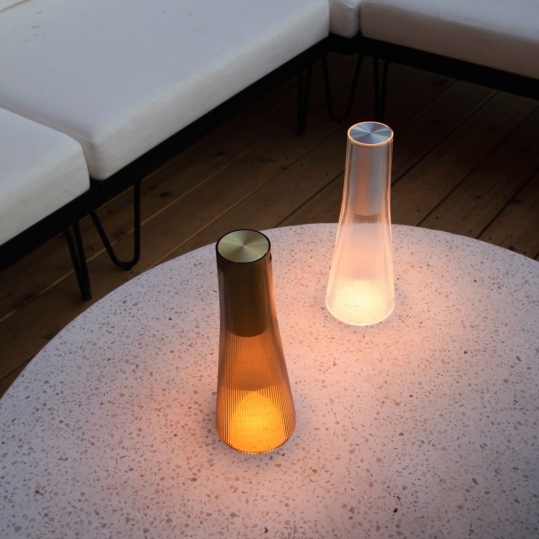 "Amber and white illuminated table lamps on a speckled surface, surrounded by minimalist white seating."