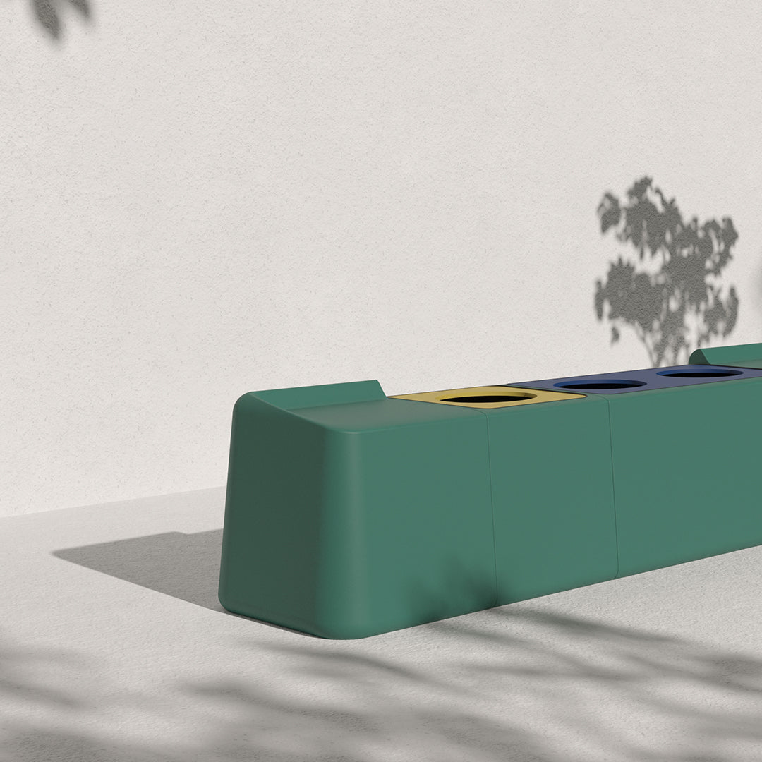 Modern green bench with yellow, blue, and black circular accents. Minimalist design against a neutral backdrop.