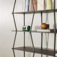 Modern black shelf with geometric design, featuring textured white backdrop and colorful decor accents.