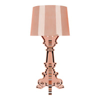 Rose gold lamp with a striped beige and white shade, featuring an ornate base design in a glossy finish.