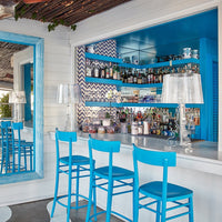 Bright blue bar stools against a white backdrop with a chevron-patterned accent wall and mirrored decor.