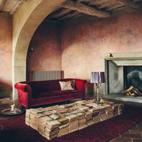 Luxurious burgundy velvet sofa with intricate floral patterns on beige walls and a rich red patterned rug.