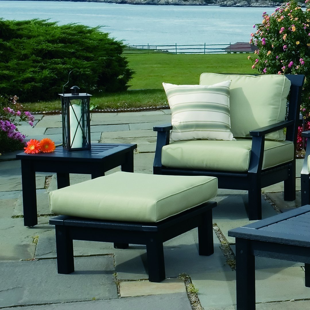 "Light green cushions on dark frames, featuring a striped accent pillow, set against a natural outdoor backdrop."