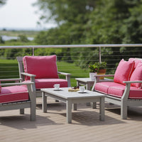 Outdoor furniture set featuring vibrant pink cushions and a light gray frame, set against a lush green background.