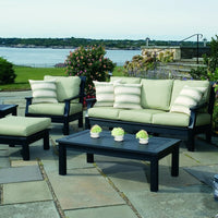 Black outdoor furniture with light green cushions and striped accent pillows, set against a scenic waterfront backdrop.