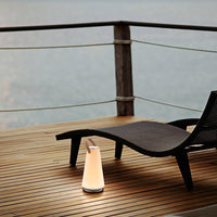 White and black modern lamp on wooden deck, featuring smooth lines and a minimalist design against a serene backdrop.