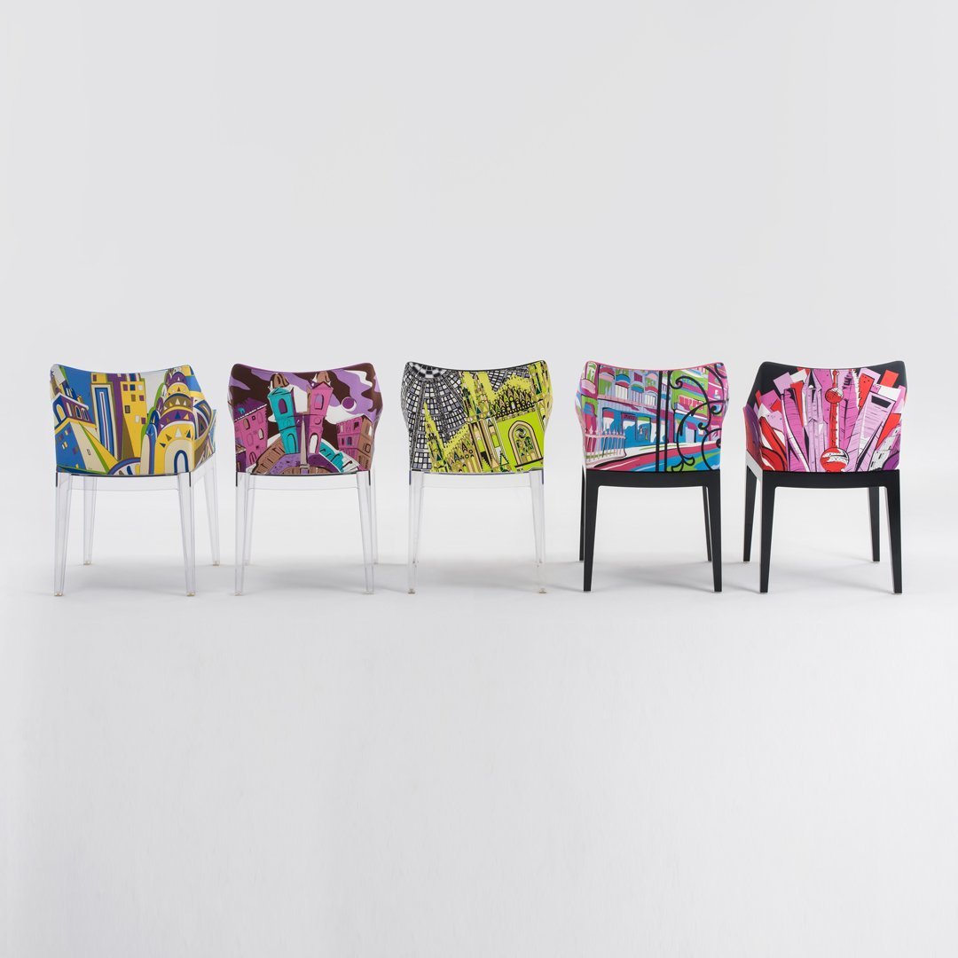 Colorful chairs with vibrant abstract patterns in blue, yellow, green, pink, and black against a neutral background.