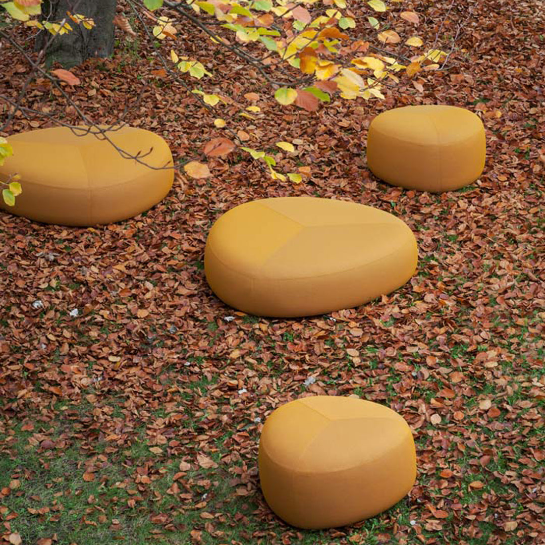 "Set of smooth, rounded, mustard-yellow outdoor seating cushions on a bed of autumn leaves."