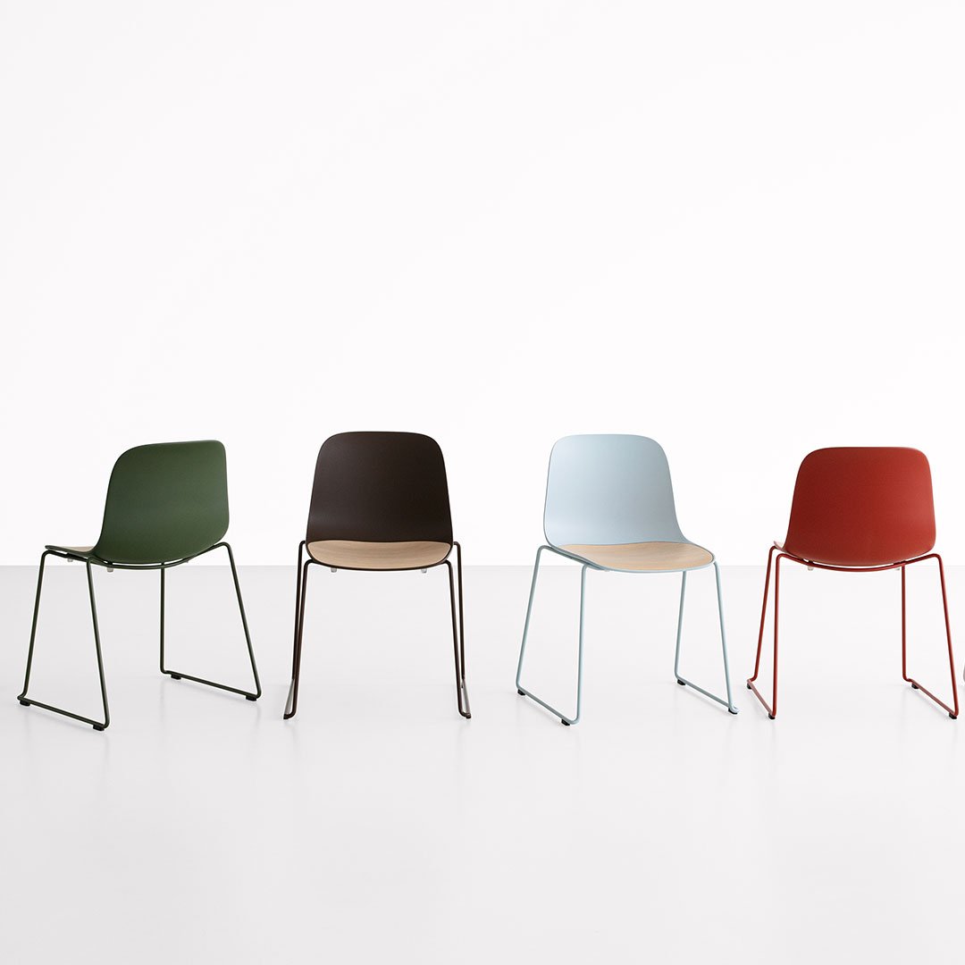 Set of four chairs in dark green, brown, light blue, and red, featuring sleek patterns and minimalist design.