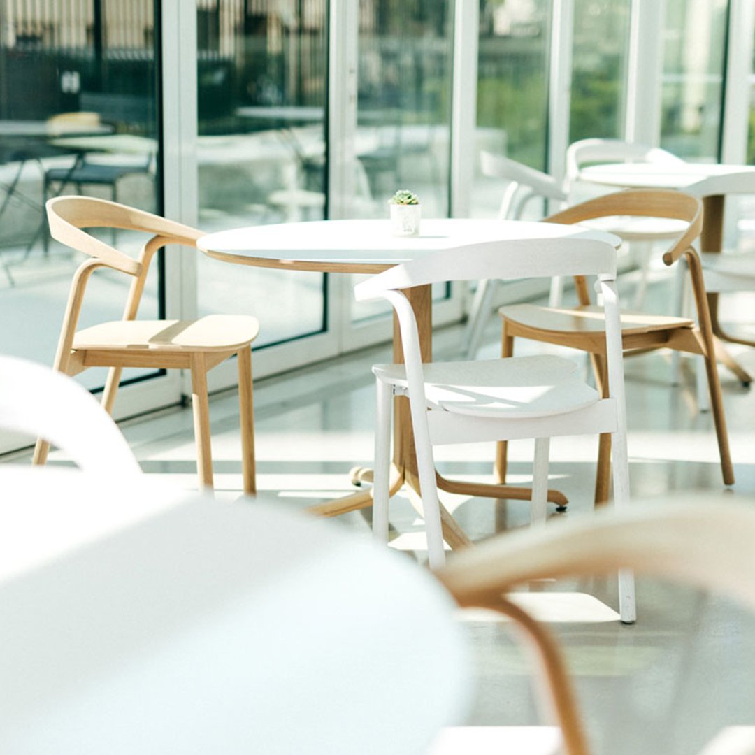 Stylish white table with natural wood chairs in a bright, airy setting, featuring clean lines and modern design.