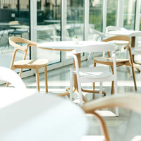 Stylish white table with natural wood chairs in a bright, airy setting, featuring clean lines and modern design.