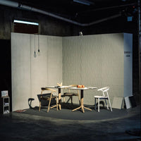 Minimalist grey walls with subtle texture, light wood furniture, and black flooring create a modern, stylish setting.