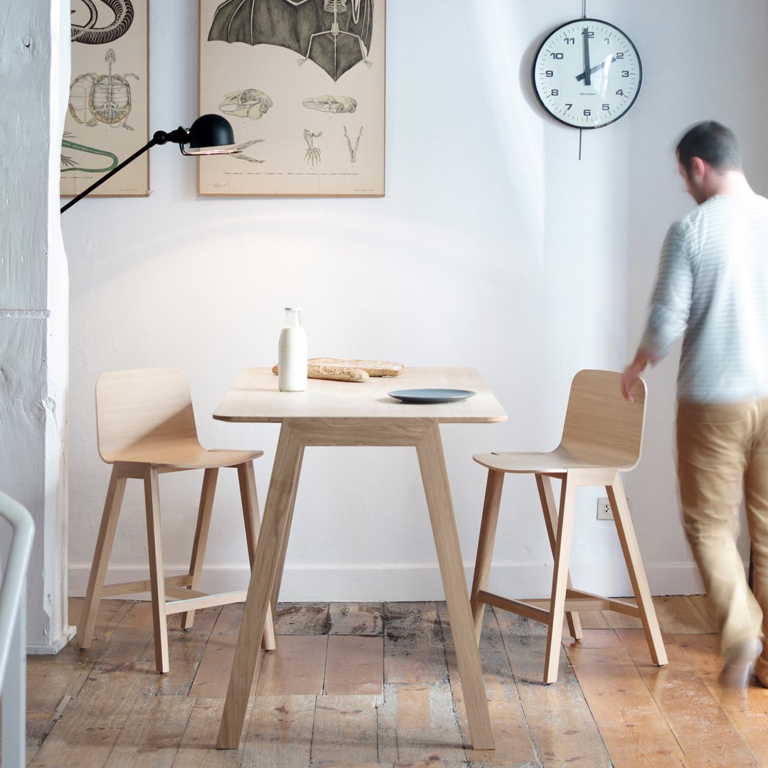 Light wood table with natural finish, complemented by beige chairs in a minimalist, modern setting. Clean lines and soft hues.