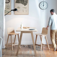 Light wood table with natural finish, complemented by beige chairs in a minimalist, modern setting. Clean lines and soft hues.