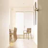 Neutral tones with light wood accents, featuring a minimalist chair against a bright, airy backdrop.