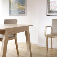 Light wood table with beige chairs, featuring a minimalist design and subtle, neutral tones in a bright interior setting.