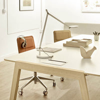 "Modern office workspace with a white desk, beige leather chairs, and minimalist decor in soft, neutral tones."
