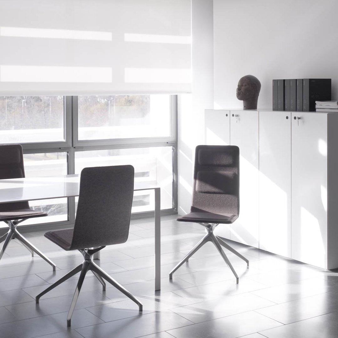 Modern gray chairs with sleek lines, white table, and minimalist decor in a bright, airy room.