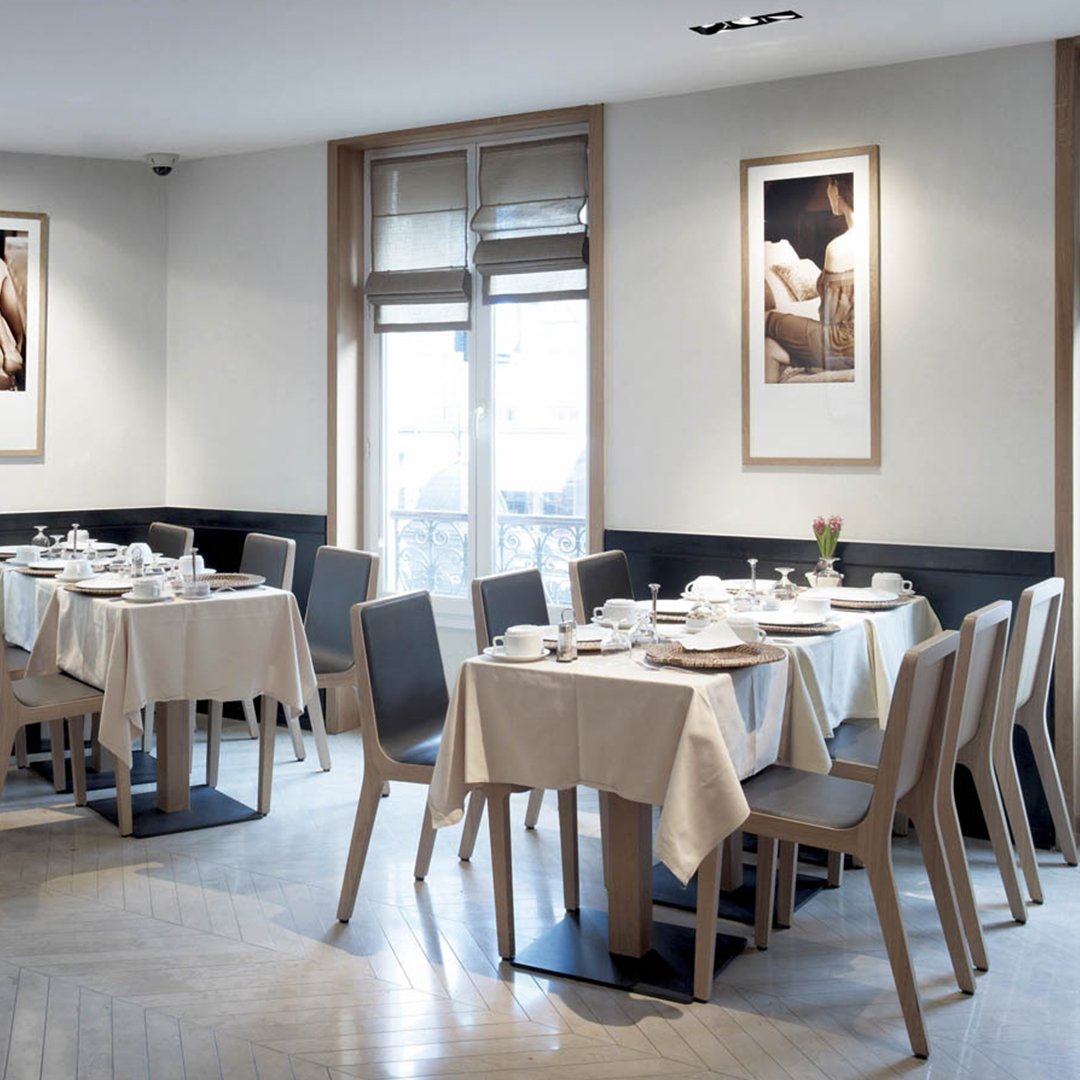 Elegant dining room with neutral-toned tables and chairs, featuring light wood and soft beige fabrics in a minimalist design.