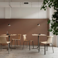 Minimalist dining area featuring beige chairs, brown wall, and sleek black accents for a modern look.