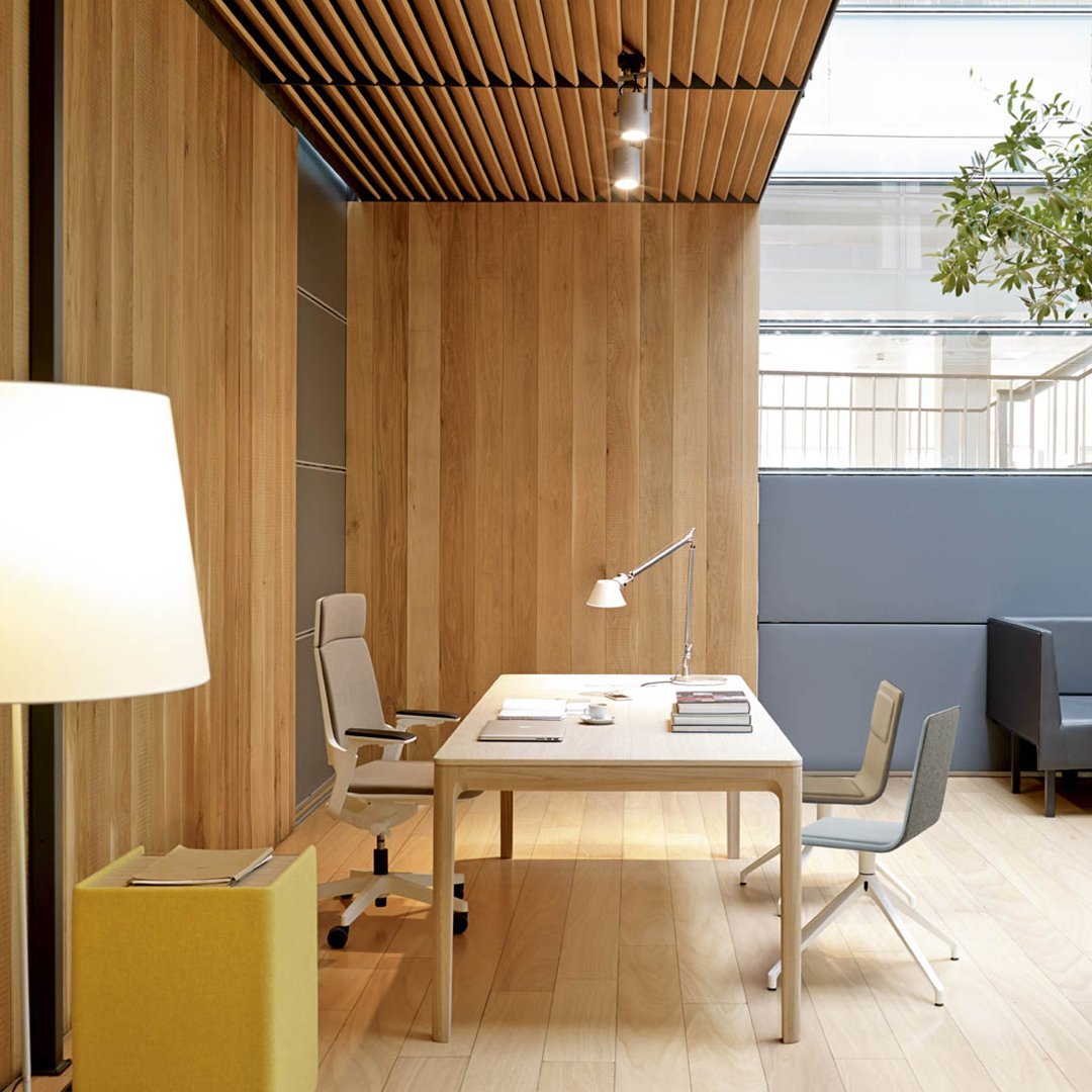 Modern office interior featuring wood panels, gray accents, and a pop of yellow in the lamp and office storage.