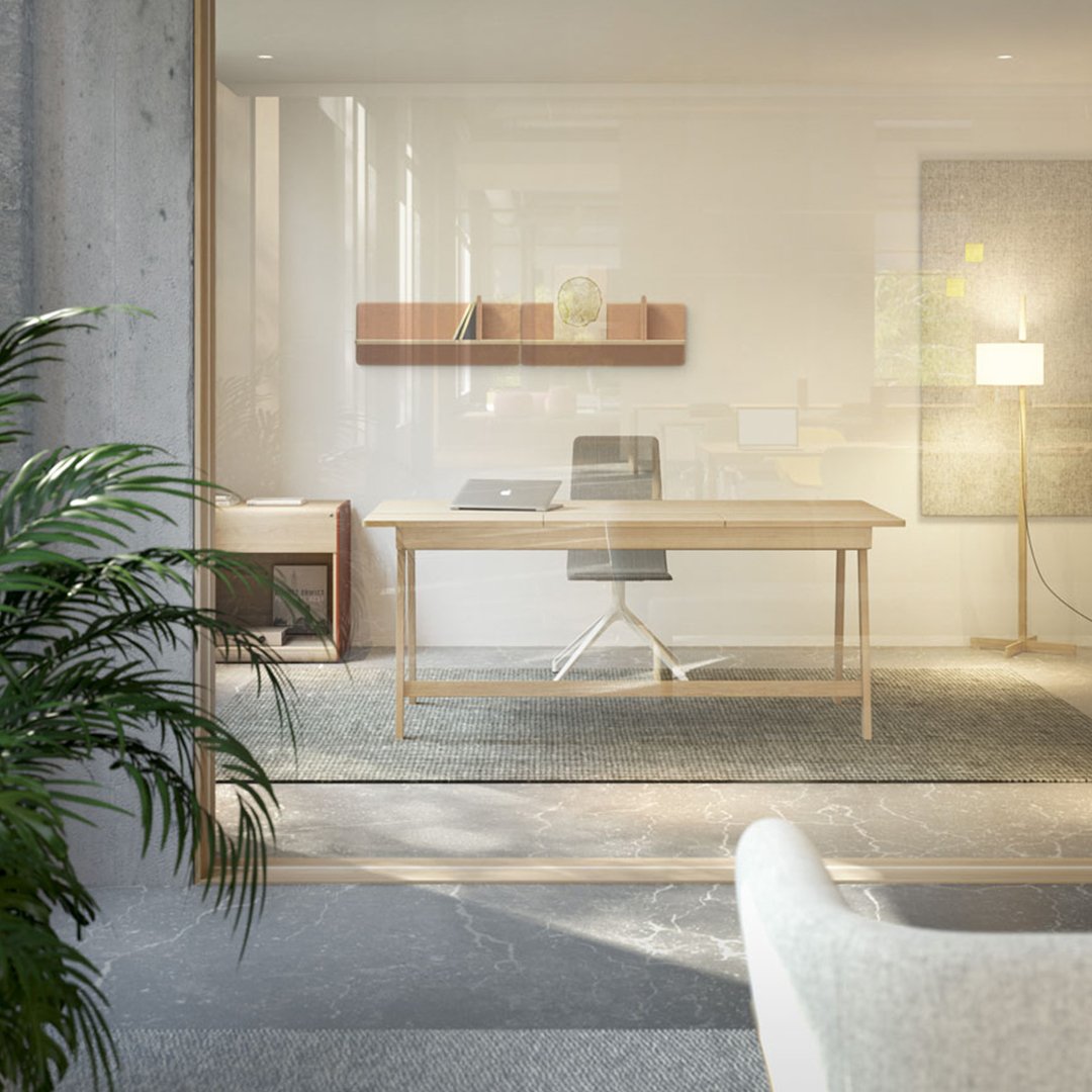 Modern office space featuring a light wood desk, gray carpet, and soft green plant against a neutral color palette.