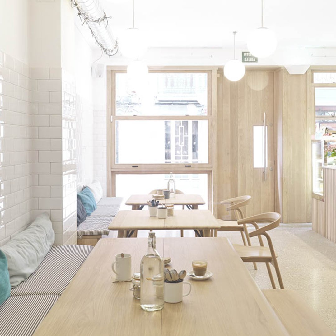 Bright white walls, natural wood tones, soft blue accents, and minimalistic decor create a serene atmosphere.