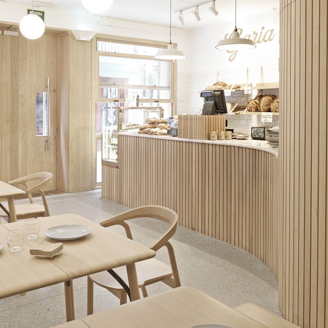 Light wood tones with smooth vertical lines and neutral beige accents create a cozy, modern café ambiance.