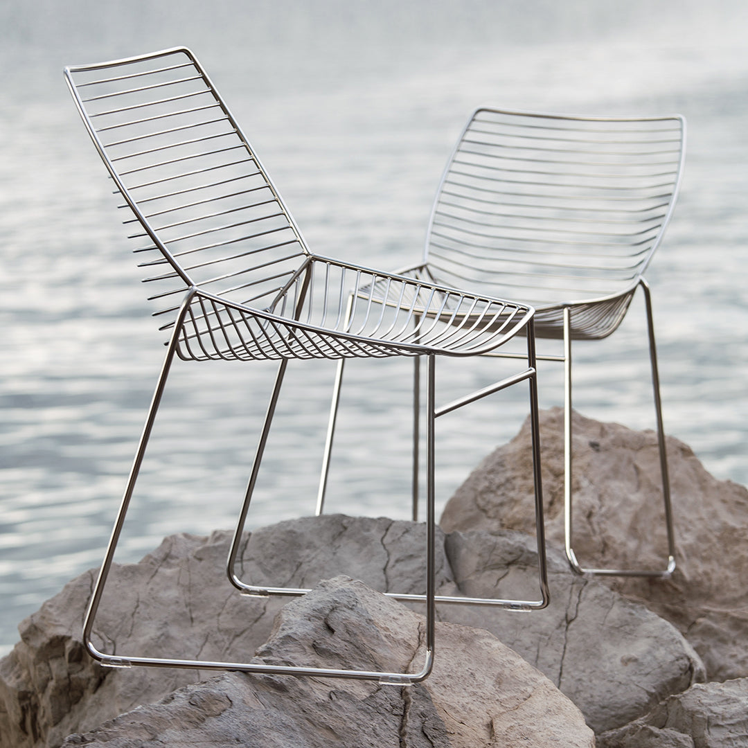 Modern silver wire chairs with a sleek, minimalist design, featuring an open pattern and smooth, polished finish.