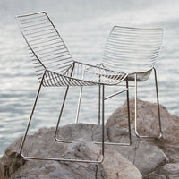 Modern silver wire chairs with a sleek, minimalist design, featuring an open pattern and smooth, polished finish.