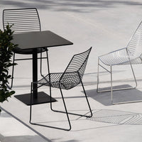 Black metal table with three wireframe chairs in black and white, featuring sleek, modern lines and minimalist design.